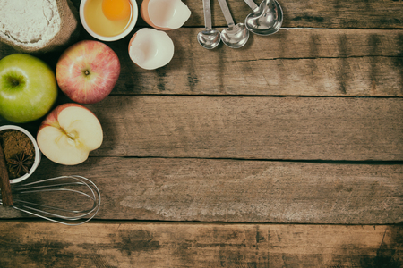 Bakery background comprise apples,wheat flour,egg and cinnamon on rustic wood table with copy space.Prepare ingredient for baking apple cake on wood table. Top view bakery background concept.の写真素材