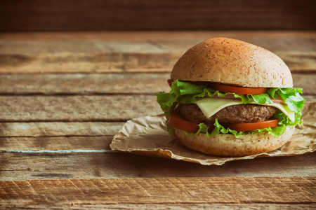 Homemade hamburger on plaid napkin with french fries. Delicious sandwich hamburger with meat or pork ham cheese and fresh vegetable. Hamburger or sandwich is the popular fast food for brunch or lunch.の写真素材