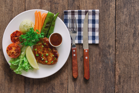 Barbecue pork steak on white plate served with barbecue sauce and vegetables. Pork steak for lunch or dinner on wood table. Moist and soft homemade pork barbecue served with mash potato and vegetable.の写真素材