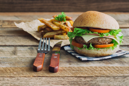 Homemade hamburger on plaid napkin with french fries. Delicious sandwich hamburger with meat or pork ham cheese and fresh vegetable. Hamburger or sandwich is the popular fast food for brunch or lunch.の写真素材