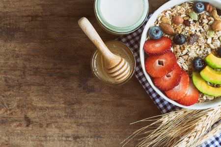 Muesli or granola on white bowl with fresh fruits nuts and cereal. Granola top with blueberries strawberries and avocado served with milk and honey for breakfast.Granola is healthy food for dieting.の写真素材