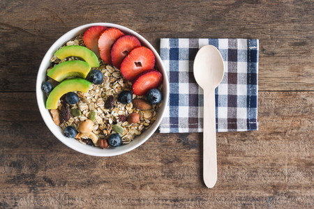 Muesli or granola on white bowl with fresh fruits nuts and cereal. Granola top with blueberries strawberries and avocado served with milk and honey for breakfast.Granola is healthy food for dieting.の写真素材