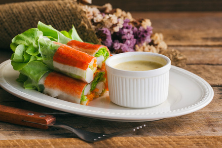 Fresh spring rolls with fresh vegetable and crab stick served with spicy salad cream dipping sauce. Rolls salad or fresh spring roll on white plate, healthy delicious food for appetizer or meal.の写真素材