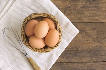 Fresh eggs in old wood basket put on white napkin. Prepare fresh chicken eggs for cooking or bakery on wood rustic wood table. Top view or flat lay of eggs with copy space for background or wallpaper.の写真素材