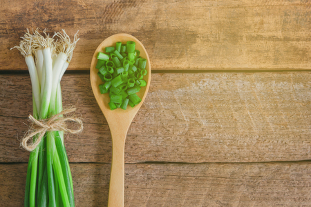 Fresh spring onion tie with rope on wood table. Close up chopped scallions or spring onion in top view flat lay.Prepare spring onion for cooking. Food and vegetable concept for background or wallpaperの写真素材
