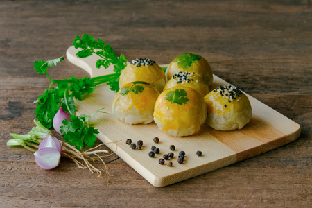 Chinese pastry or moon cake on wood cutting board with some ingredient on wooden table in side view with copy space.の写真素材