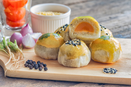 Delicious Chinese pastry or moon cake on wood cutting board with some ingredient on wooden table in side view with copy space for afternoon tea or coffee break. Homemade bakery concept.の写真素材