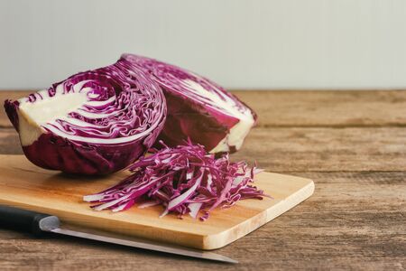 Chopped or sliced fresh purple cabbage on cutting board to shredded with knife kitchen on wood table with copy space. Prepare vegetable for cooking cabbage salad or coleslaw. Homemade food concept.の写真素材