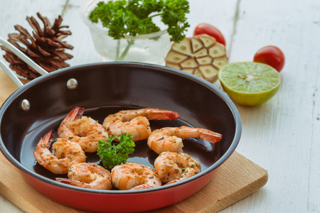 Grilled shrimp with spice served on red fried pan on white wood table with copy space. Delicious and goodness prawn steak for special lunch or dinner. Homemade food concept of seafood menu.の写真素材