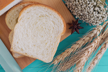 Sliced soft and sticky delicious white bread on wood cutting board prepare for breakfast on blue wooden table in top view flat lay to present bread texture or pattern.の写真素材
