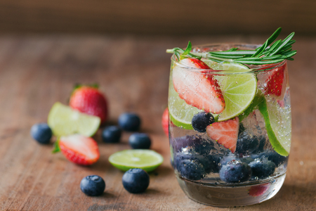 Infused water made from blueberry strawberry and lemon in sparkling mineral water look so freshness and healthy. Mixed fruit mojito on wood table with copy space. Summer refreshing drink concept.の写真素材