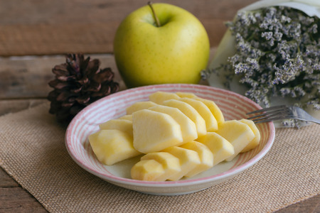 Fresh Shinano gold apple cut and sliced to piece ready to eat on plate put on wood table. Prepare delicious and healthy fruit for snack with family. Sweet sour juicy and crisp apple breed from Japan.の写真素材