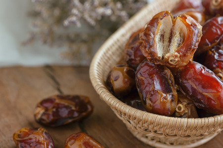 Khalas date palm on wooden basket in side view with copy space on wood table for background. Dates fruit is food for Ramadan or medjool. Delicious dried fruit with sweet taste and have high fiber.の写真素材