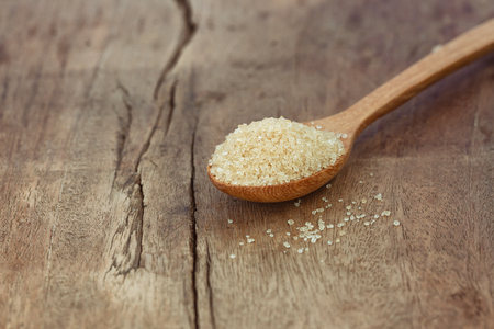 Natural brown sugar or no bleach sugar on wooden spoon put on wood table in side view with copy space. Sweet seasoning for good health concept. Ingredient prepared for cooking bakery and beverage.の写真素材