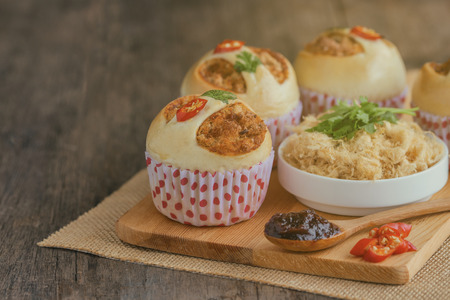 Homemade cup of soft and sticky bun with dried shredded pork or pork floss and shrimp roasted chili paste on wood table with ingredients. Thai style delicious bread with sweet and spicy taste.の写真素材