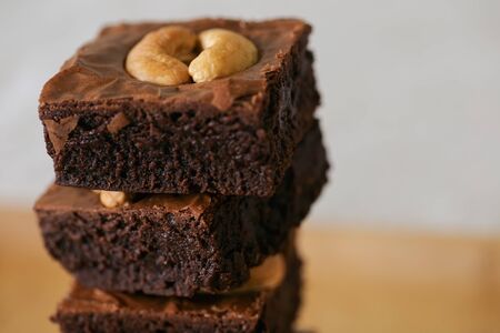 Dark chocolate fudge brownies topping cashew nuts stack on wood plate with copy space. Delicious...