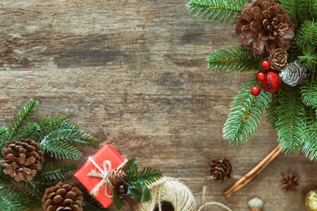 Christmas plank background decoration pine leaves and cones, gift box and holly balls on wood table with copy space in top view flat lay. Vintage wooden Christmas wallpaper for xmas celebration.の写真素材
