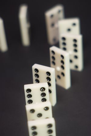 white plastic domino trail over black background
