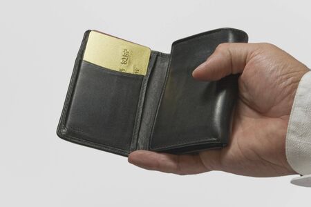 hand holging a black wallet and gold credit card