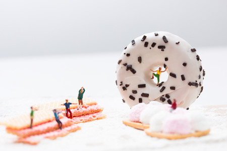 Miniature people, watching a woman climb a donutの写真素材