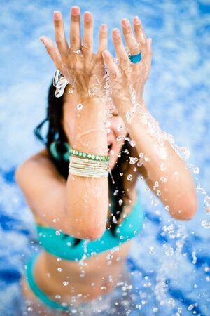 water splashing from above on a woman in a swimming poolの写真素材