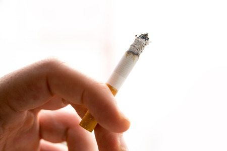 Male hand holding a cigarette on white backgroundの写真素材