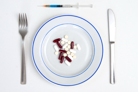 Medical Meal of pills and tablets on a plate with Fork, Knife and Syringeの写真素材