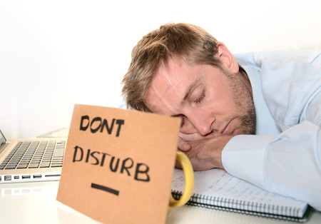 Dont Disturb written cardboard sign and Young Student or Businessman Overwhelmed  sleeping 