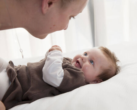 Young mother playing with sweet baby girl at home