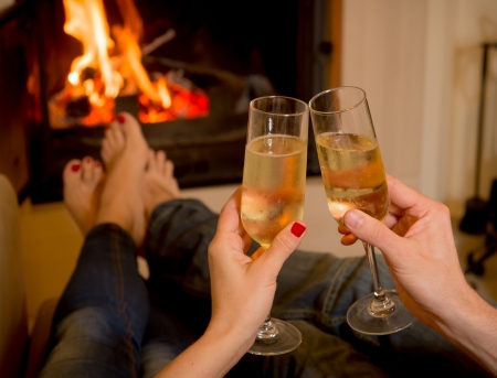 close up of young couple drinking champagne in front of a open wood fireの写真素材