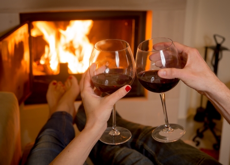 close up of young couple drinking wine in front of an open wood fire  の写真素材