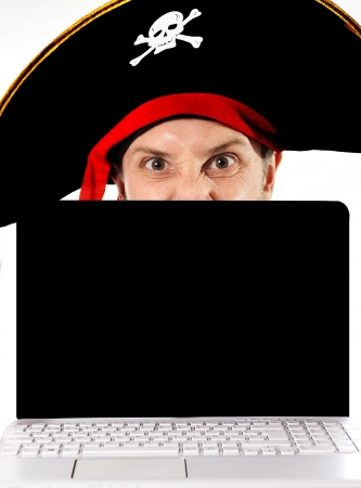 Young man in pirate costume and Computer representing illegal downloads and copyright violation isolated on white backgroundの写真素材