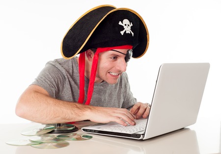 man dressed as a pirate on his computer downloading music and movies on a white background  の写真素材