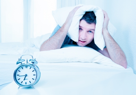 sleeping man disturbed by alarm clock early morning の写真素材
