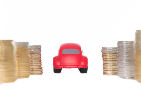 close-up of a red toy car driving through a pile of euro coins on a white background  の写真素材