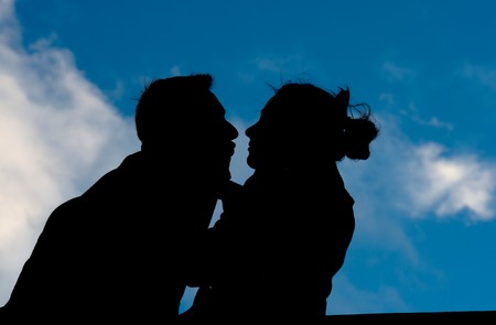 young couple in silhouette holding a love heart shape pillowの写真素材