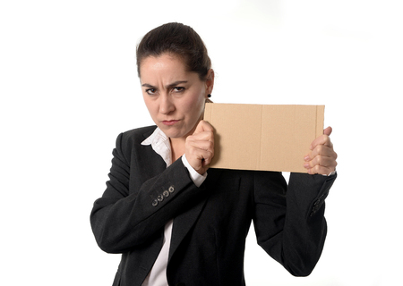 overworked angry business woman in stress wearing a business suit holding a blank sign as copy space on a white  の写真素材