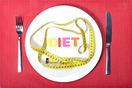measure tape as meal on dish with fork and knife in diet conceptの写真素材