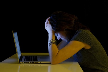 Young student woman alone at desk with computer crying desperate suffering cyber mobbing and...