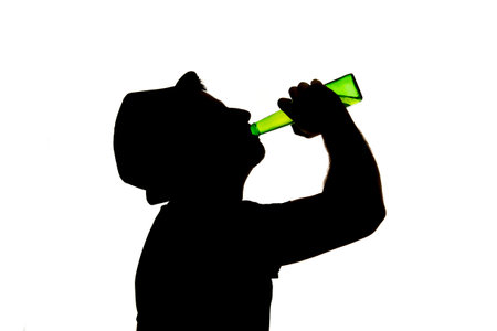 silhouette of alcoholic drunk young man with hat  drinking beer bottle feeling depressed falling...