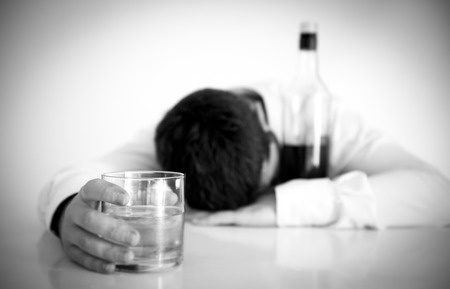 black and white portrait of young attractive business man with beard  wearing blue shirt and tie drunk and drinking  Whisky sleeping on office desk at work isolated on clear の写真素材