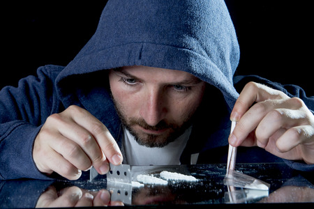 depressed sick looking Cocaine addict man, sniffing cocaine using razor blade for cutting the drug...