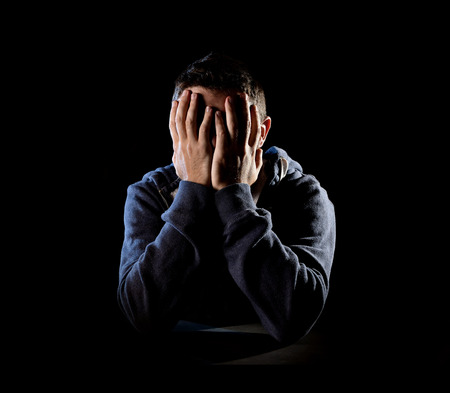 young desperate man suffering and covering face with hands in deep depression , pain and emotional...