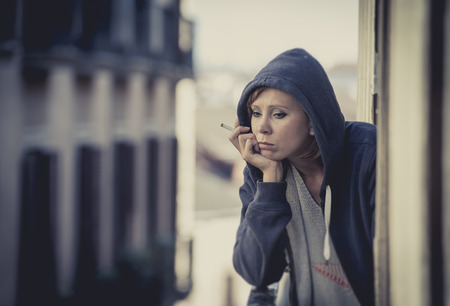 young attractive woman suffering depression and smoking in stress outdoors at home balcony terrace...