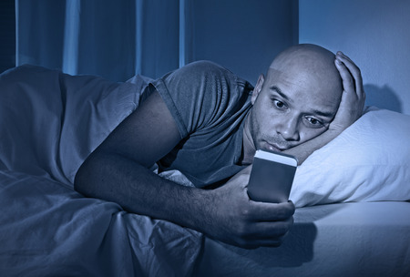 young cell phone addict man awake at night in bed using smartphone for chatting, flirting and sending text message in internet addiction and mobile abuse concept young cell phone addict man awake at night in bed using smartphone for chatting, flirting and sending text message in internet addiction and mobile abuse concept