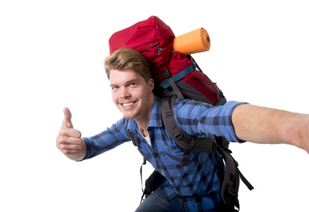 young attractive  backpacker tourist taking selfie photo carrying backpack ready for travel and adventure on vacations route isolated on white backgroundの写真素材