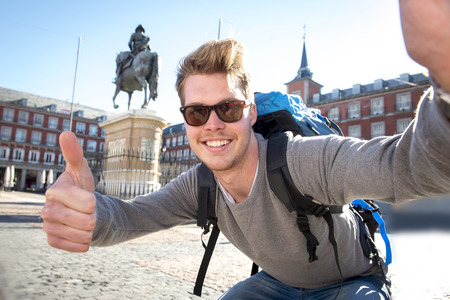 young attractive student backpacker tourist taking selfie photo with mobile phone outdoors enjoying holidays travel destination in tourism and exploring concept