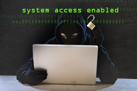 hacker man in black hood and mask with computer laptop holding lock in dangerous dark look hacking...