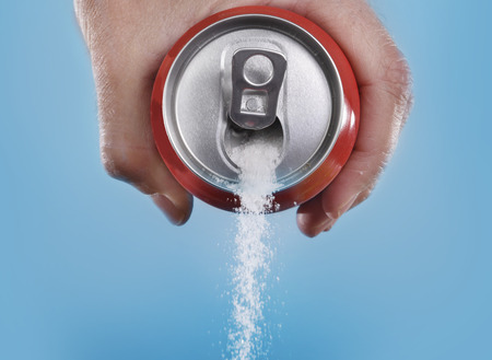hand holding soda can pouring a crazy amount of sugar in metaphor of sugar content of a refresh...