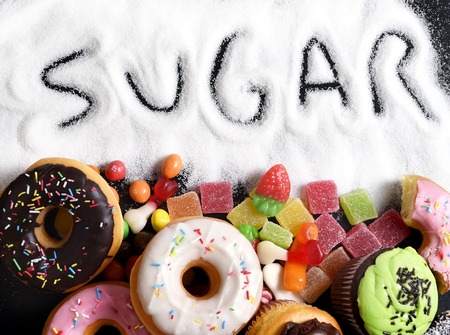 mix of sweet cakes, donuts and candy with sugar spread and written text in unhealthy nutrition, chocolate abuse and addiction concept, body and dental careの写真素材